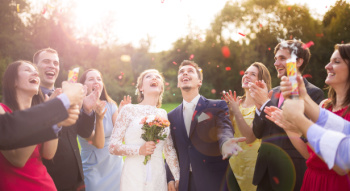 wedding guests throwing confeti with a couple